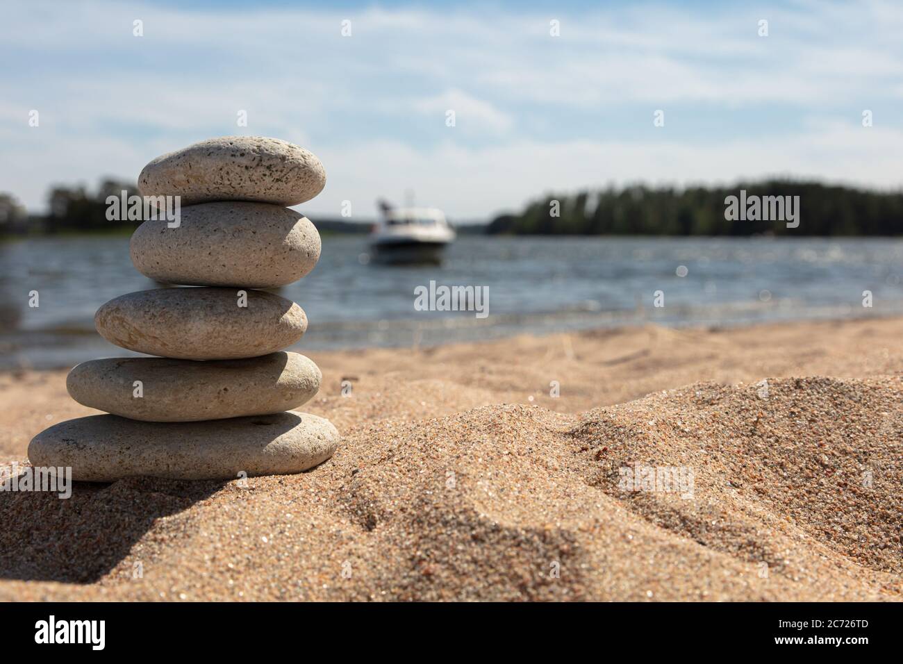 All'alba, le pietre nella piramide sulla sabbia della spiaggia. L'oggetto è a fuoco, lo sfondo è sfocato. Foto di alta qualità Foto Stock
