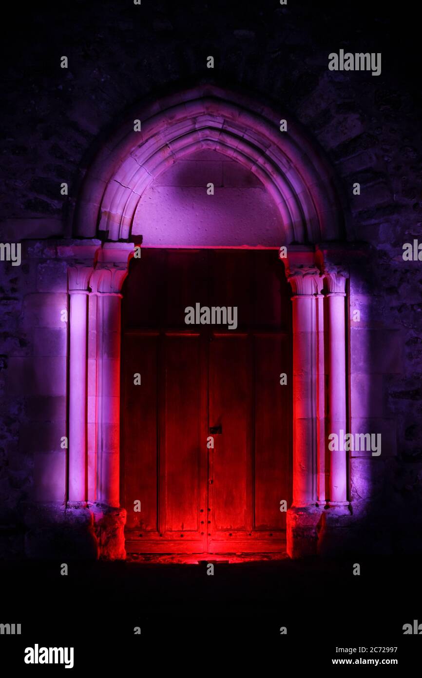 Sessione di pittura leggera in un luogo mistico la notte. Porta in legno di una chiesa con scultura gotica illuminata con led. Foto Stock
