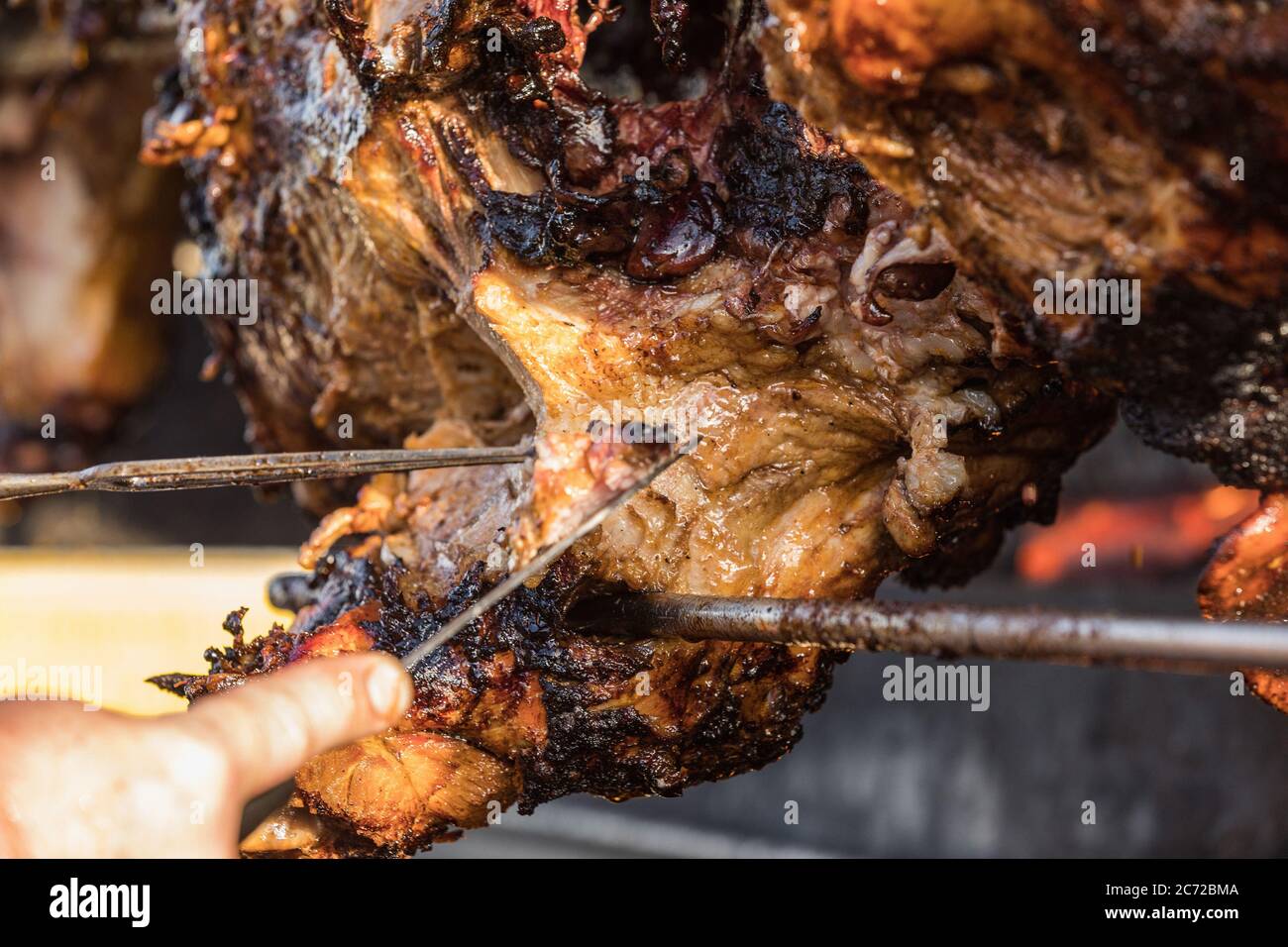 Porzionamento di maiale arrosto, affettamento di carne.. Maiale grigliato carbone tradizionale e fuoco. Il maiale viene arrostito intero su un fuoco aperto. Maiale sullo spiedo. Foto Stock