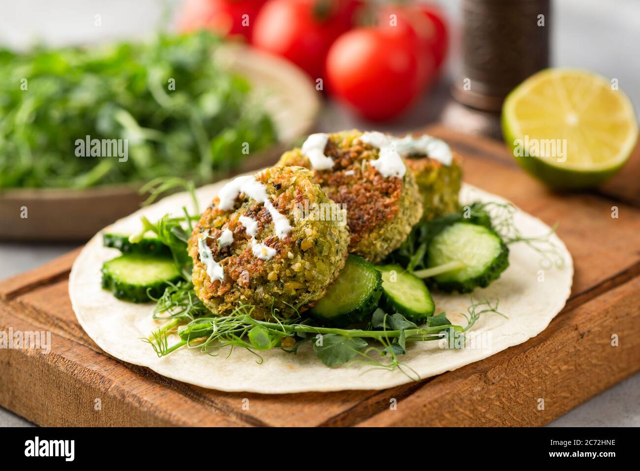 Tortilla vegana con falafel, cetriolo, micrograni e salsa. Tortilla wrap sano fatto in casa Foto Stock