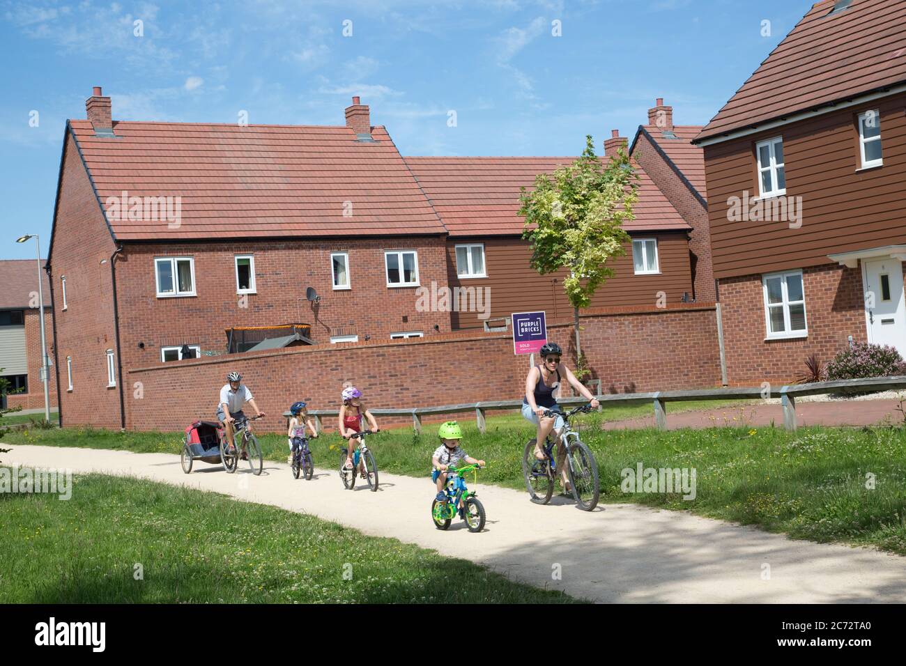 Famiglia in bicicletta a Long Marston Garden Village, proposto lo sviluppo di comunità di 4000 case attraenti ben progettato di alta qualità in passato Foto Stock