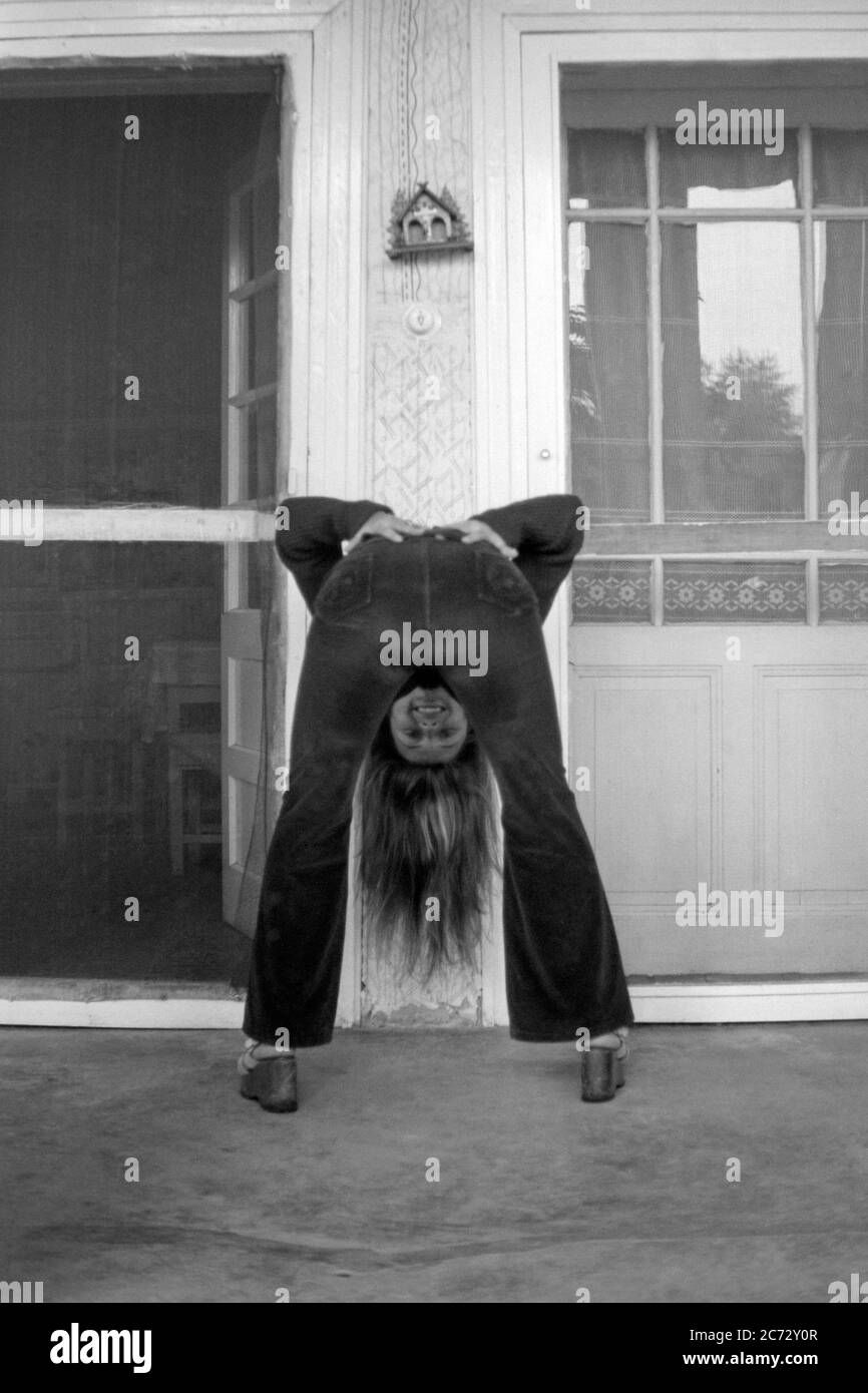 giovane donna sorridente che indossa pantaloni svasati che si piega sulla veranda della sua casa ungherese tradizionale anni 60 ungheria Foto Stock