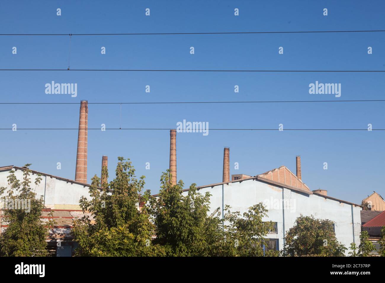 Panorama di un complesso industriale abbandonato con i suoi tipici alti camini in mattoni rossi mentre i cavi sono visibili di fronte, a Pancevo, Serbia. P Foto Stock