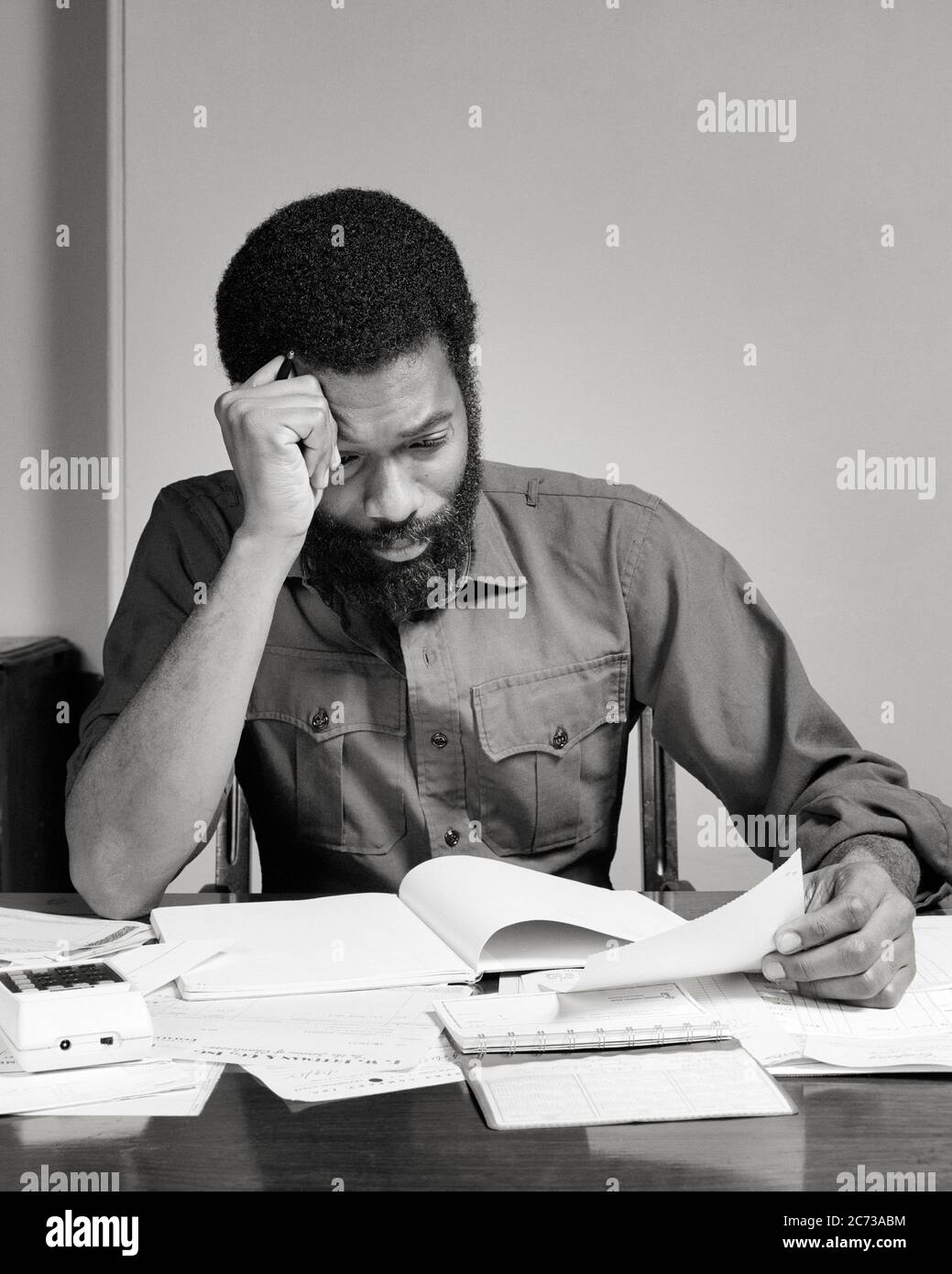 1970 PERPLESSO STANCO AFROAMERICANO UOMO PROPRIETARIO DI ABITAZIONE RIPOSO TESTA A MANO SEDUTA LAVORANDO SU CONTI PERSONALI E FATTURE - S21315 HAR001 SPAZIO COPIA HARS MEZZA LUNGHEZZA PERSONE MASCHI RISCHIO TORMENTATO B&W INTERESSATO A RIPOSARE TRISTEZZA BAFFI CONTI ANSIOSO SOPRAFFATTI STRATEGIA BAFFI AFROAMERICANI AFROAMERICANI E NERO ETNIA SUL VISO CAPELLI UMORE CONCETTUALE GLUM PROPRIETARIO DI CASA MISERABILI SOLUZIONI GIOVANE UOMO ADULTO NERO E BIANCO HAR001 VECCHIO STILE PERPLESSI AFROAMERICANI Foto Stock