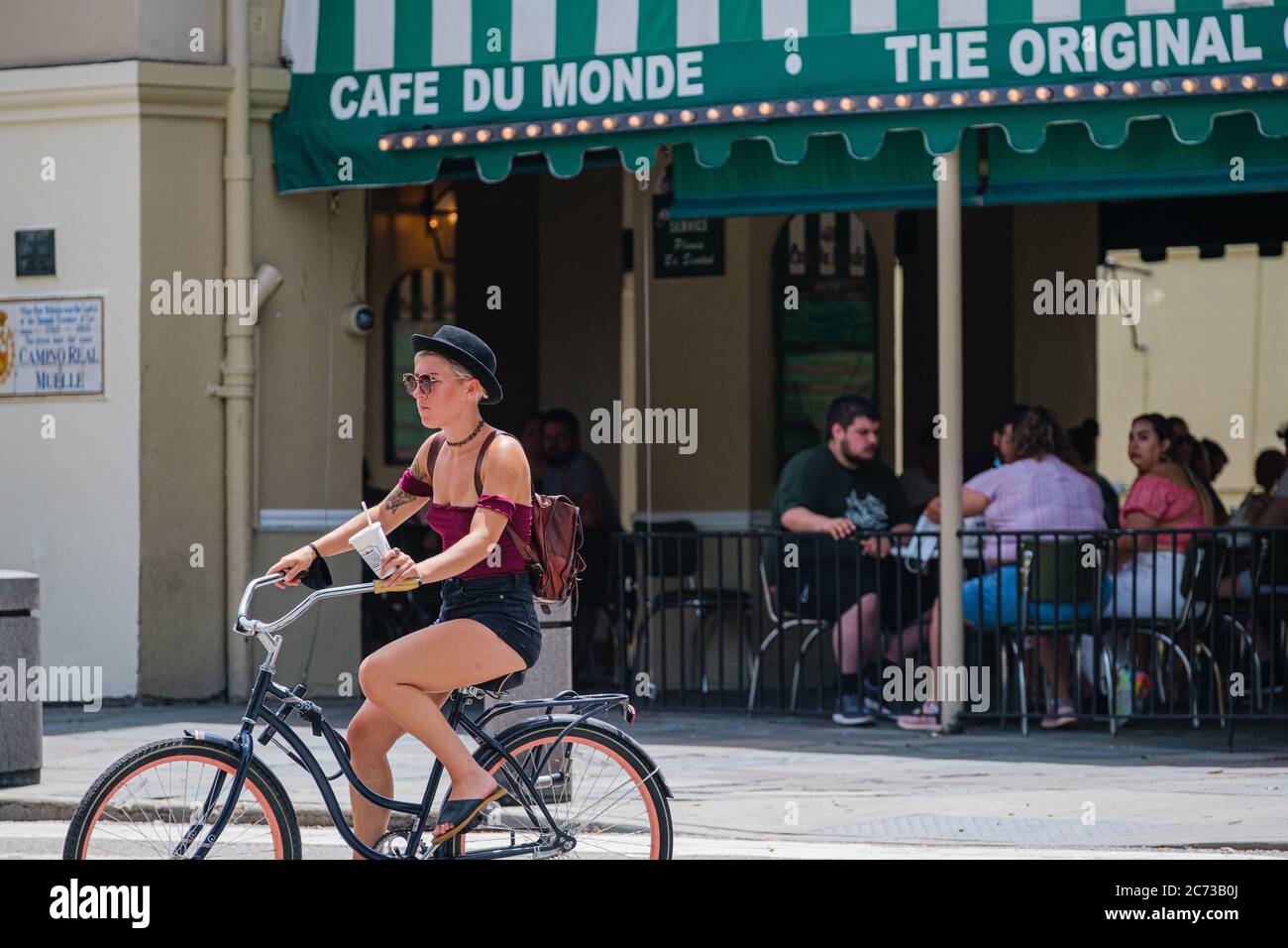 New Orleans, Louisiana/USA - 7/8/2020: La ciclista donna attraversa il Crosswalk con il Cafe Du Monde in background nel quartiere francese Foto Stock