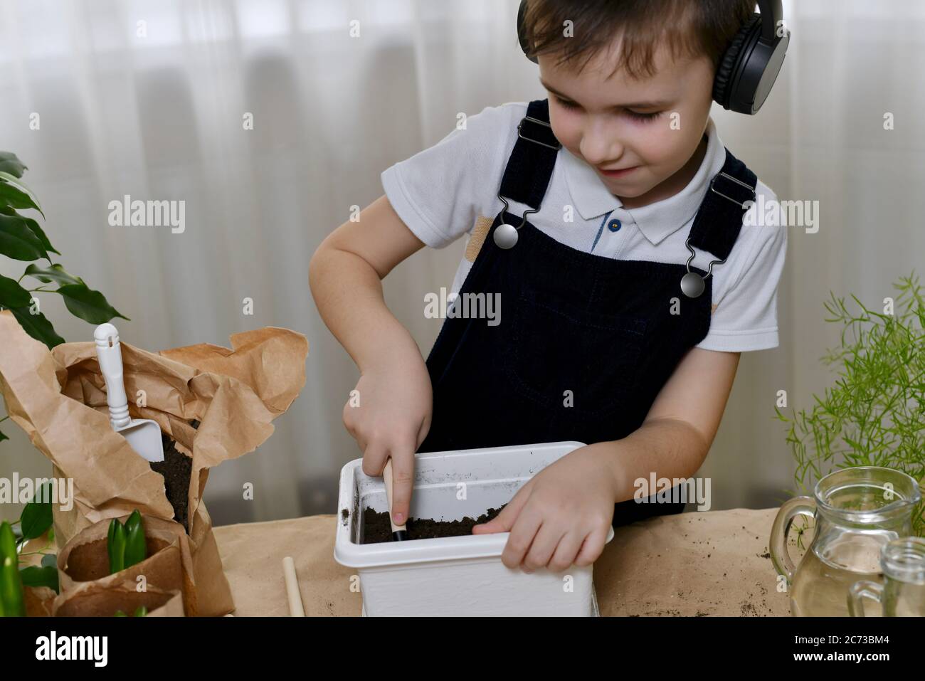 Il ragazzo, divertente danze e allenta il terreno con un attrezzo, è impegnato nella piantagione di giacinti. Foto Stock