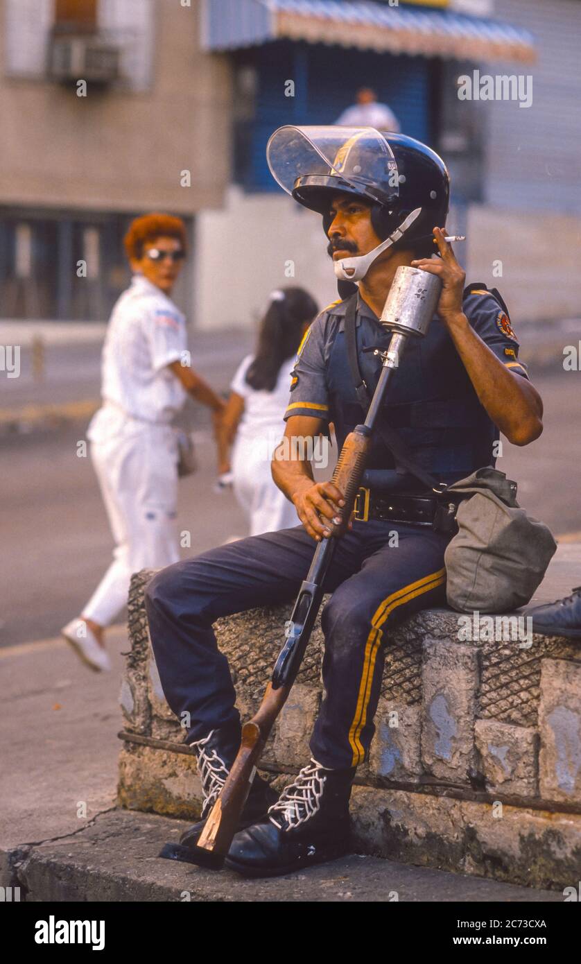 CARACAS, VENEZUELA, MARCH1989 - l'ufficiale di polizia con fucile a gas lacrimogeno si rompe, durante lo stato di emergenza durante le proteste, i disordini e i saccheggi a Caracas, conosciuto come il Caracazo. Foto Stock
