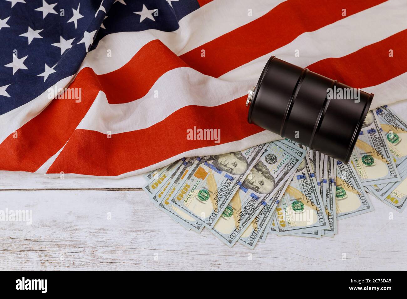 Un barile di petrolio e cento dollari banconote prezzi su un fondo di bandiera americana Foto Stock