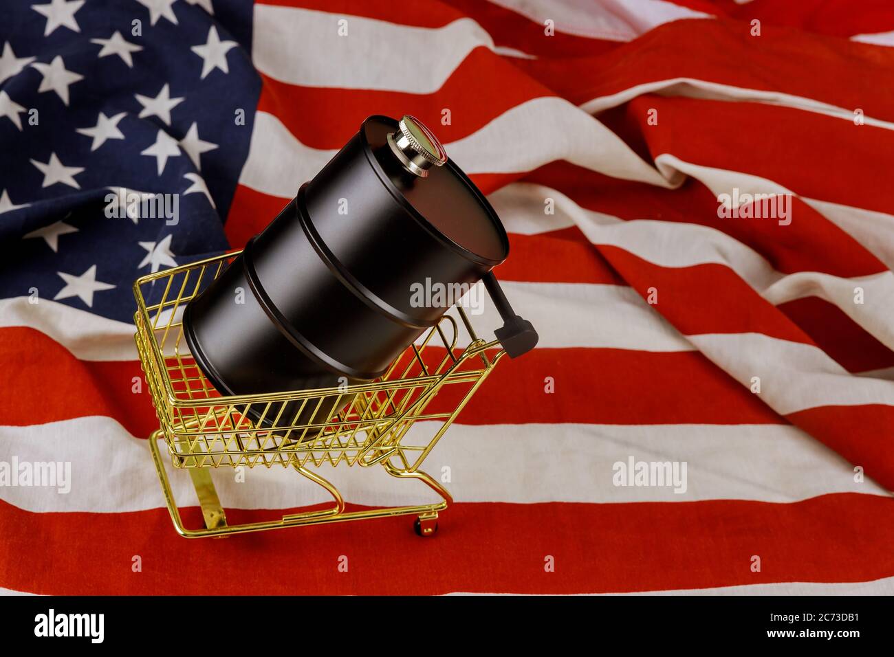 Un barile di petrolio di prezzi del petrolio in calo su un fondo di bandiera americana Foto Stock