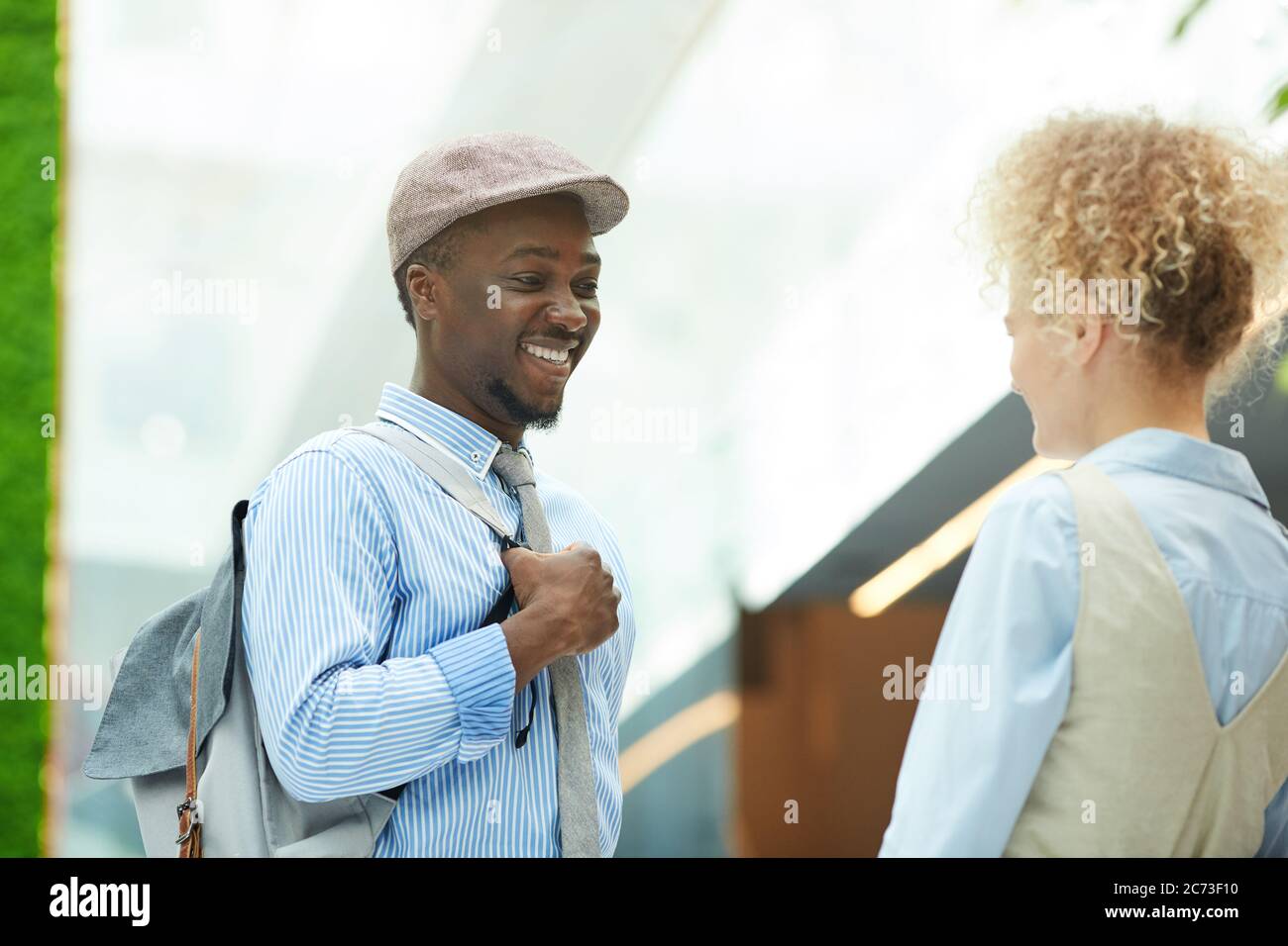 Felice uomo africano che parla con la giovane donna e sorridendo durante il loro incontro all'aperto Foto Stock