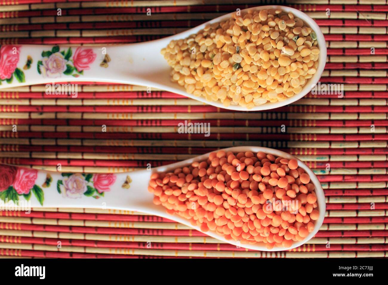 Mucchio di lenticchie rosse non cotte e piselli piccioni. Fagioli Mung e lenticchie rosse in due cucchiai isolati su sfondo colorato e testurizzato. Foto Stock Mucchio di lenticchie rosse non cotte e piselli piccioni. Fagioli Mung e lenticchie rosse in due cucchiai isolati su sfondo colorato e testurizzato. Foto Stock