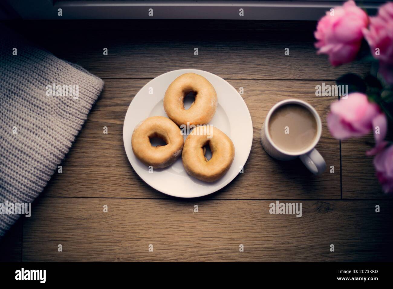 Vista di Donuts e una tazza di caffè per il tempo libero a casa durante l'inverno con una sensazione di intimita Foto Stock