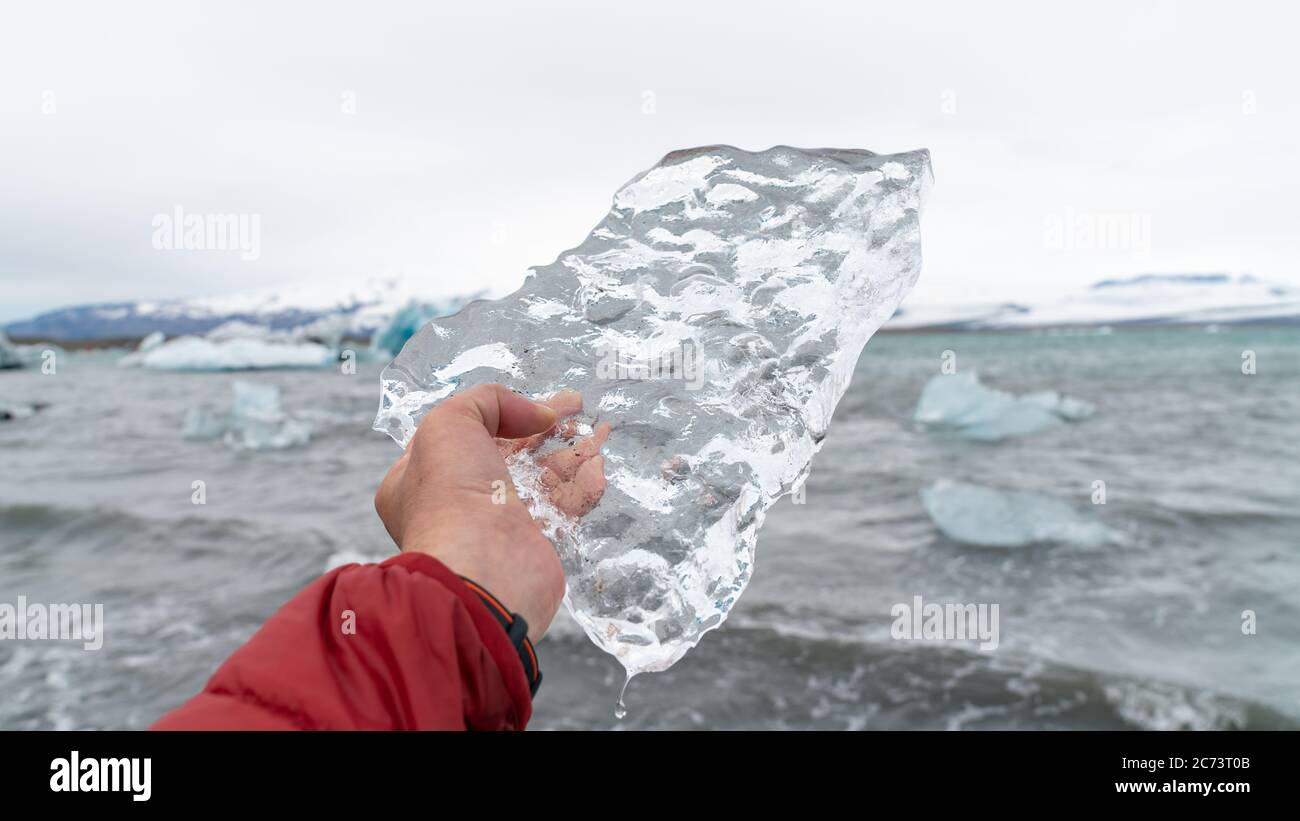 Uomo che tiene un pezzo di ghiaccio nella laguna glaciale di Jokulsarlon formata con ghiaccio fondente, Islanda. Il concetto di riscaldamento globale e cambiamento climatico Foto Stock