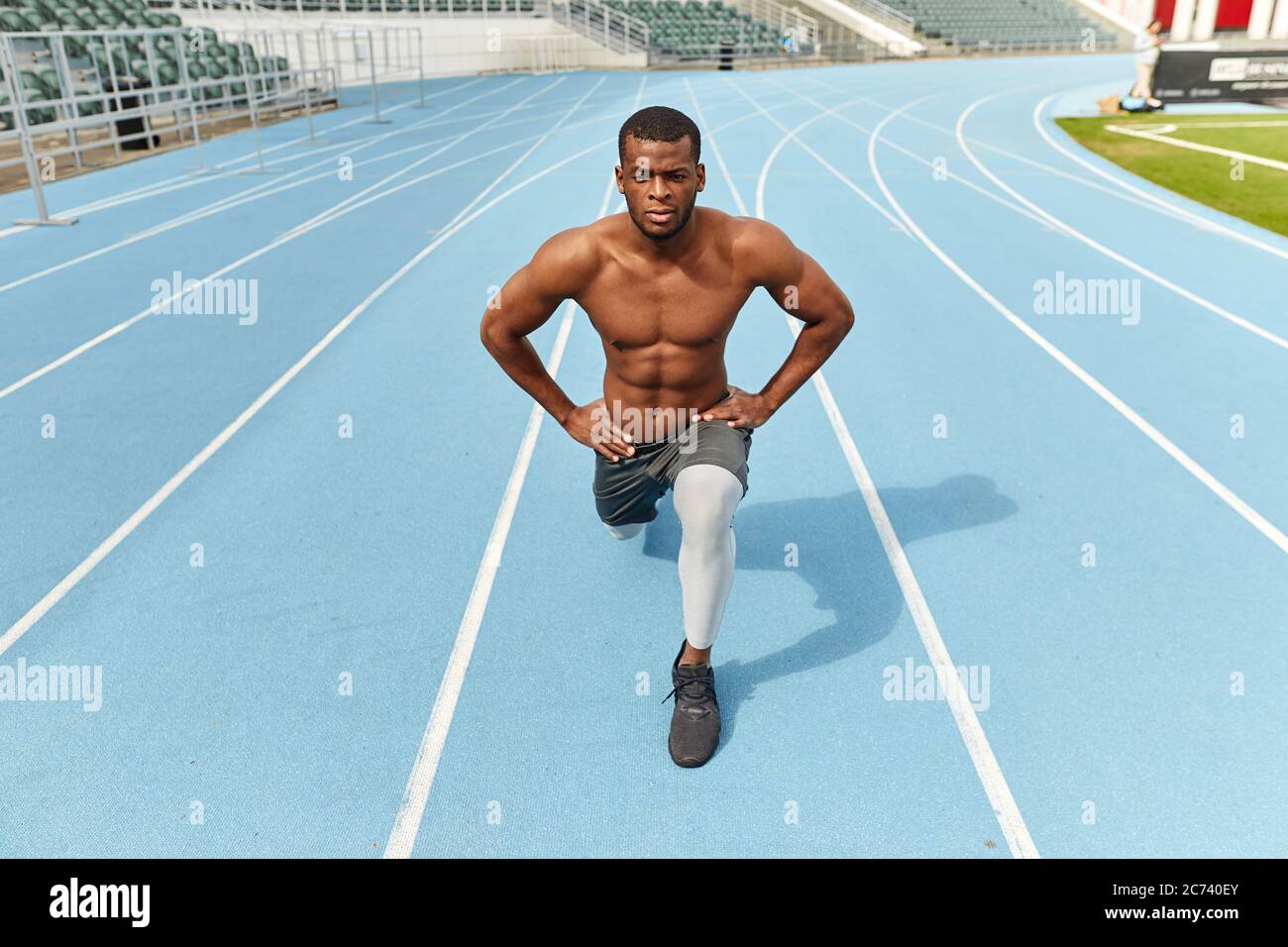 Bel forte sportivo che fa affondo, vestito di abbigliamento sportivo, all'aperto, foto a tutta lunghezza. Hobby, interesse Foto Stock