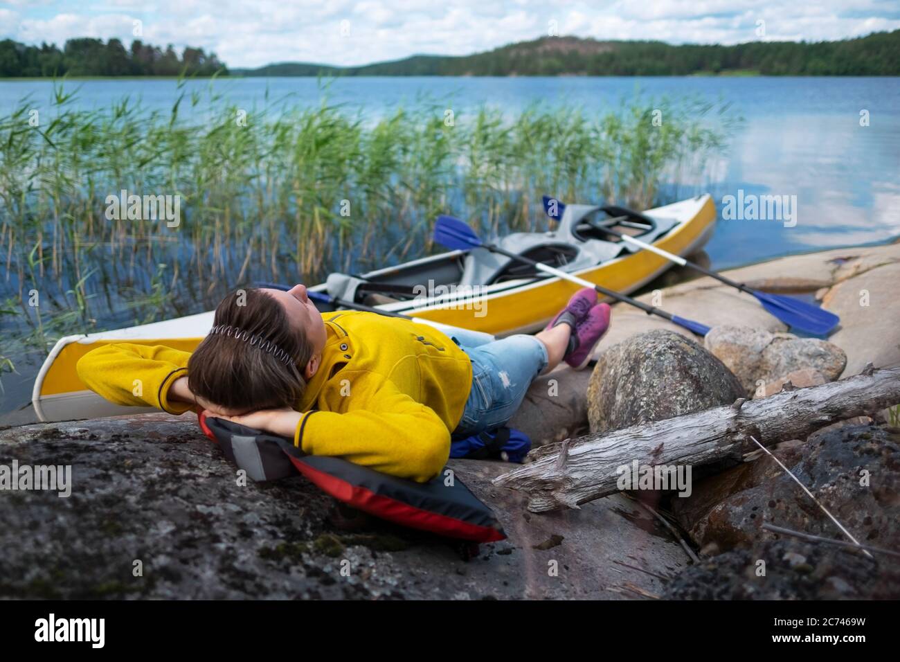Giovane caucasica che riposa sul fiume dopo il kayak. Foto Stock