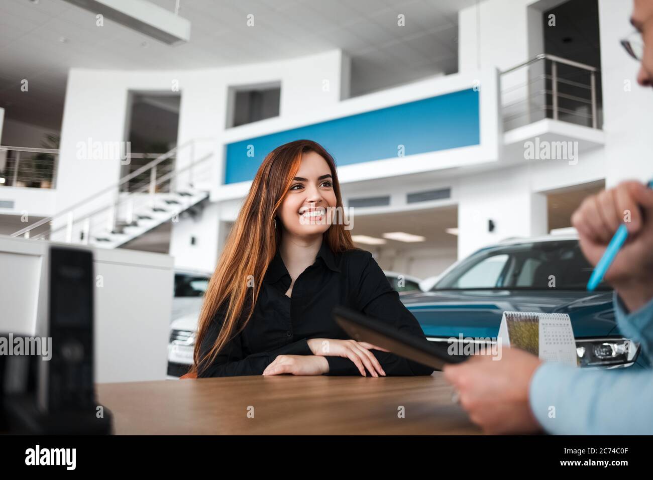 Il venditore della concessionaria di automobili spiega i dettagli del contratto al cliente femminile Foto Stock