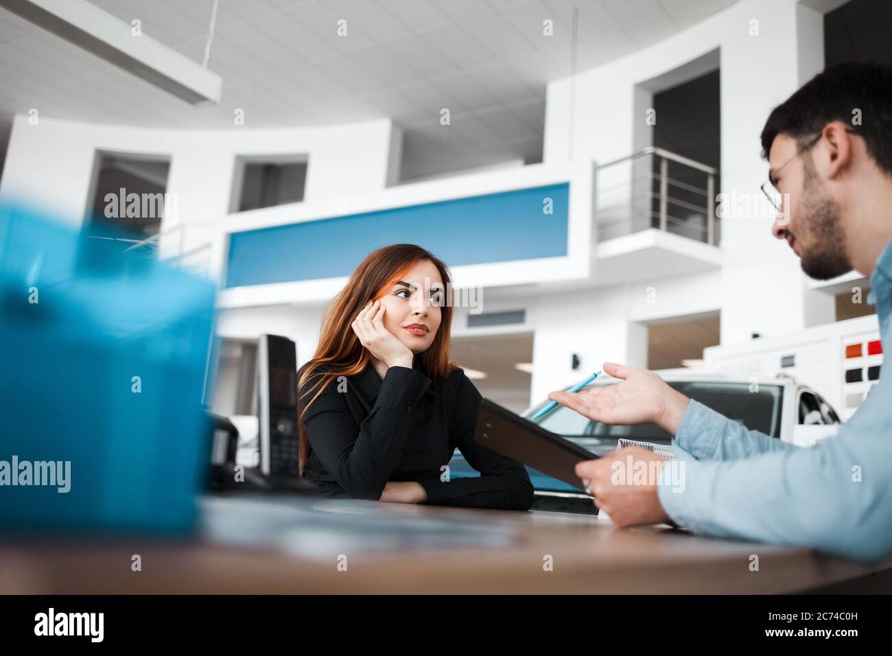 Il venditore della concessionaria di automobili spiega i dettagli del contratto al cliente femminile Foto Stock