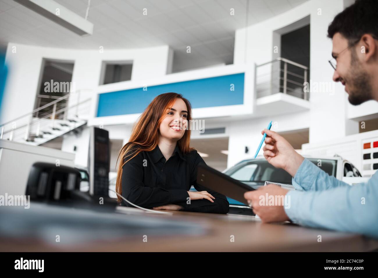 Il venditore della concessionaria di automobili spiega i dettagli del contratto al cliente femminile Foto Stock