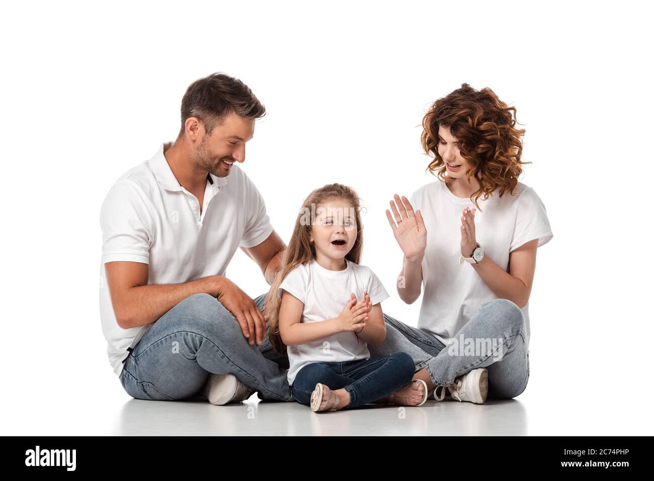 felice padre e madre che guarda la figlia carina che si aggrappano le mani su bianco Foto Stock