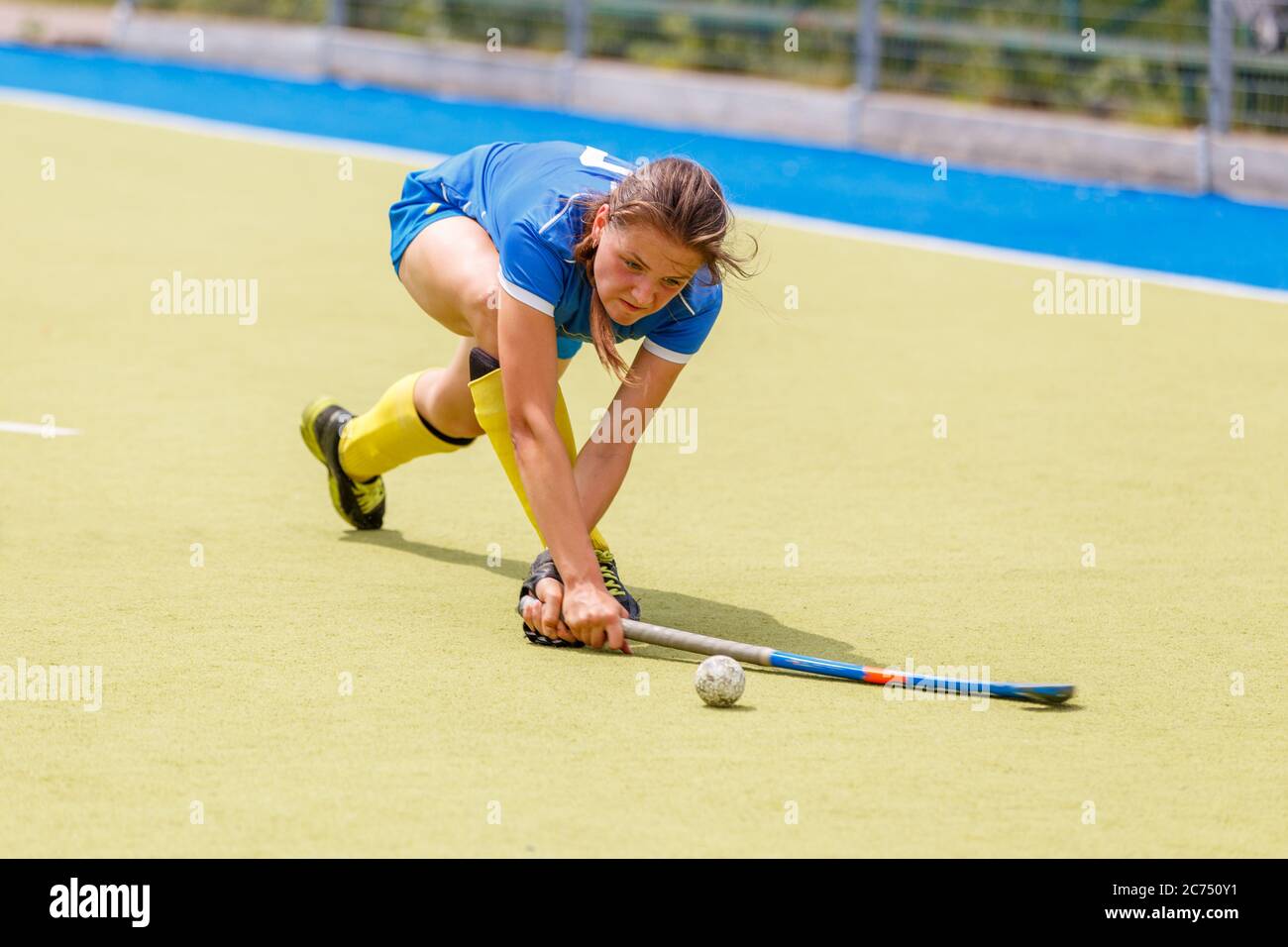 Giovane giocatore di hockey su campo che colpisce la palla sul campo. Foto Stock