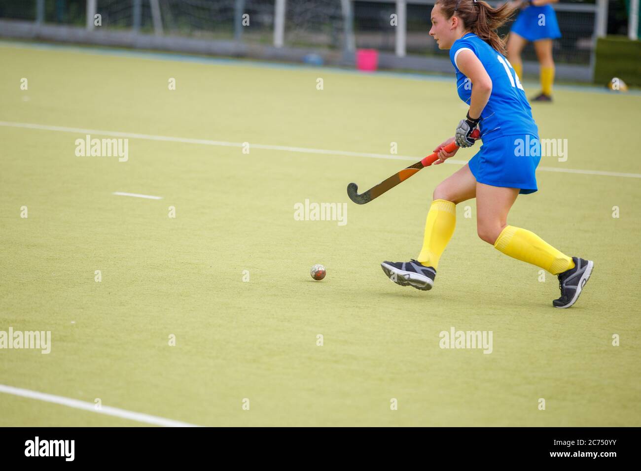 Giovane donna che gioca a hockey sul campo in campo. Immagine di gioco di hockey su campo femminile con spazio di copia Foto Stock