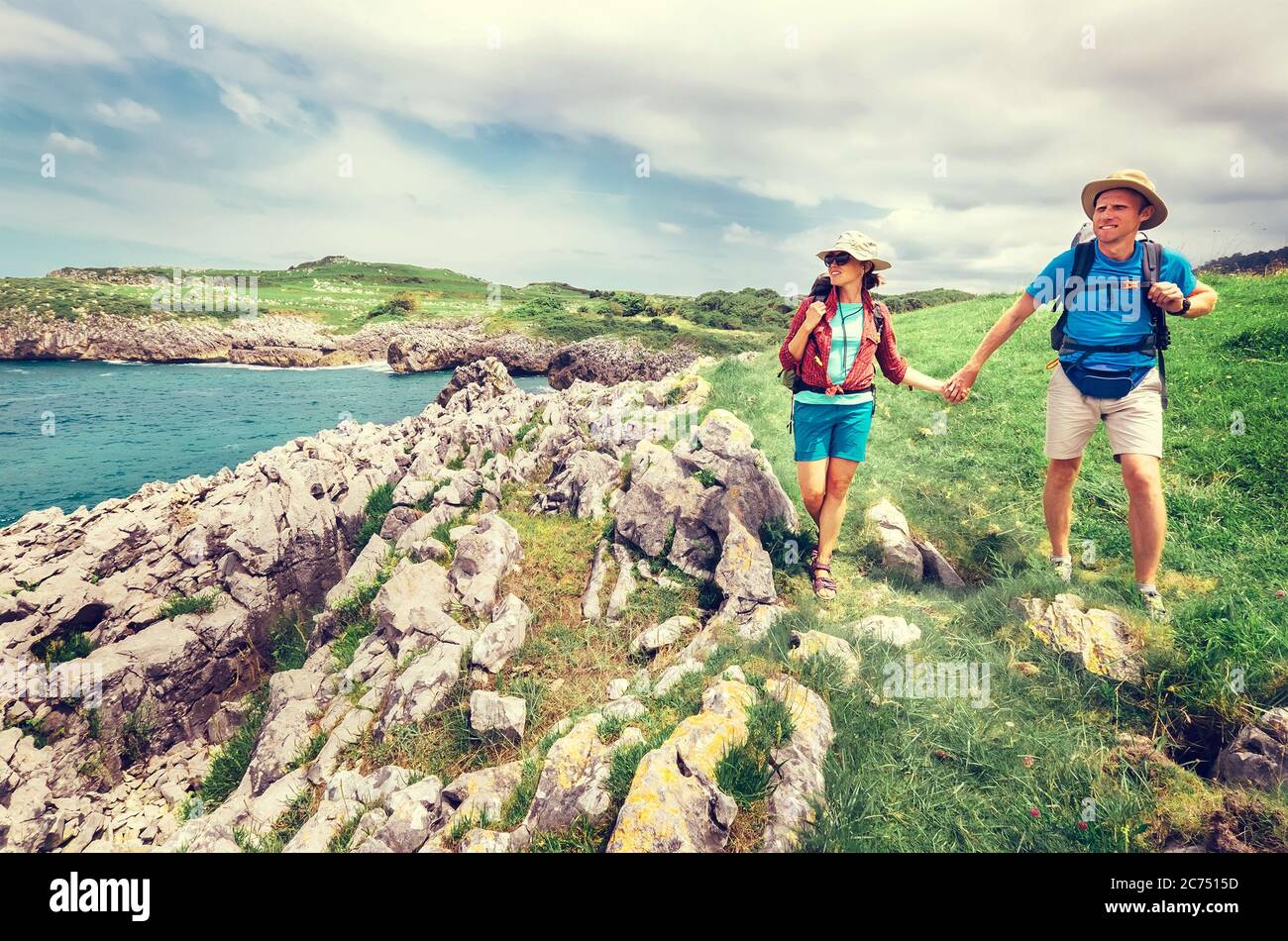 Un paio di viaggiatori zaino in spalla cammina sulla costa rocciosa dell'oceano. Asturie. Spagna Foto Stock