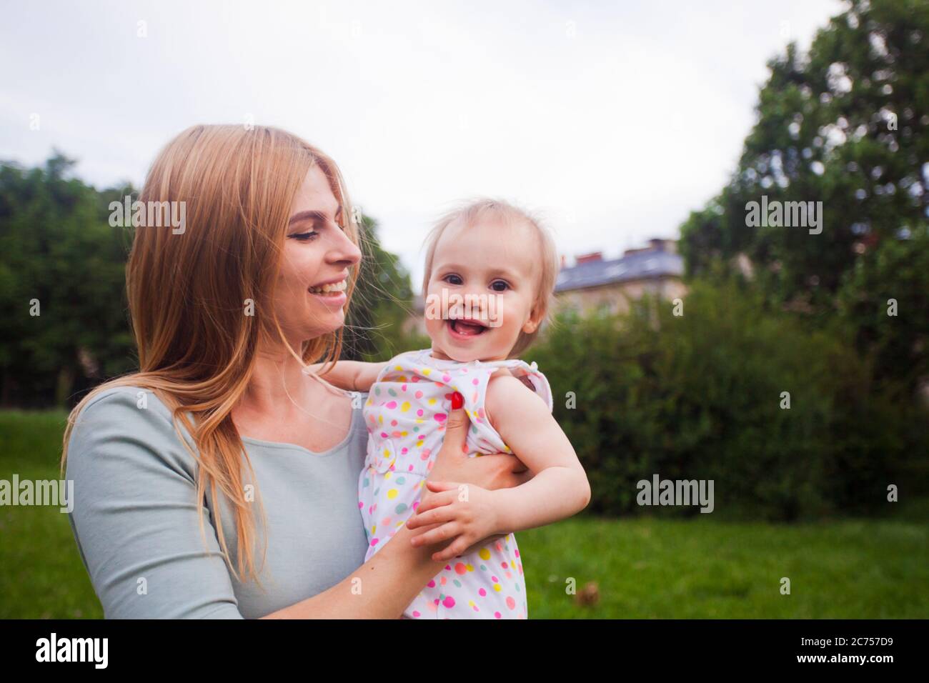 La mamma bionda sorridente e sua figlia riposano nel parco Foto Stock