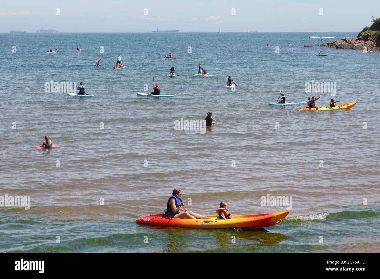 Chi si diverse a praticare sport acquatici sulla spiaggia di Broadsands, Devon Foto Stock