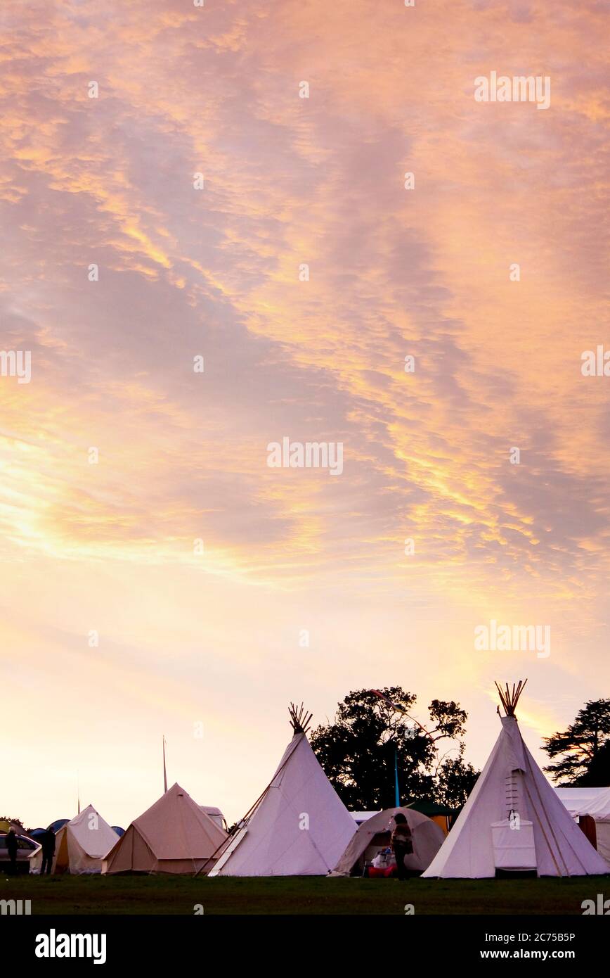 Tipis in campo glamping con ad un campeggio festival al tramonto, Norfolk Foto Stock