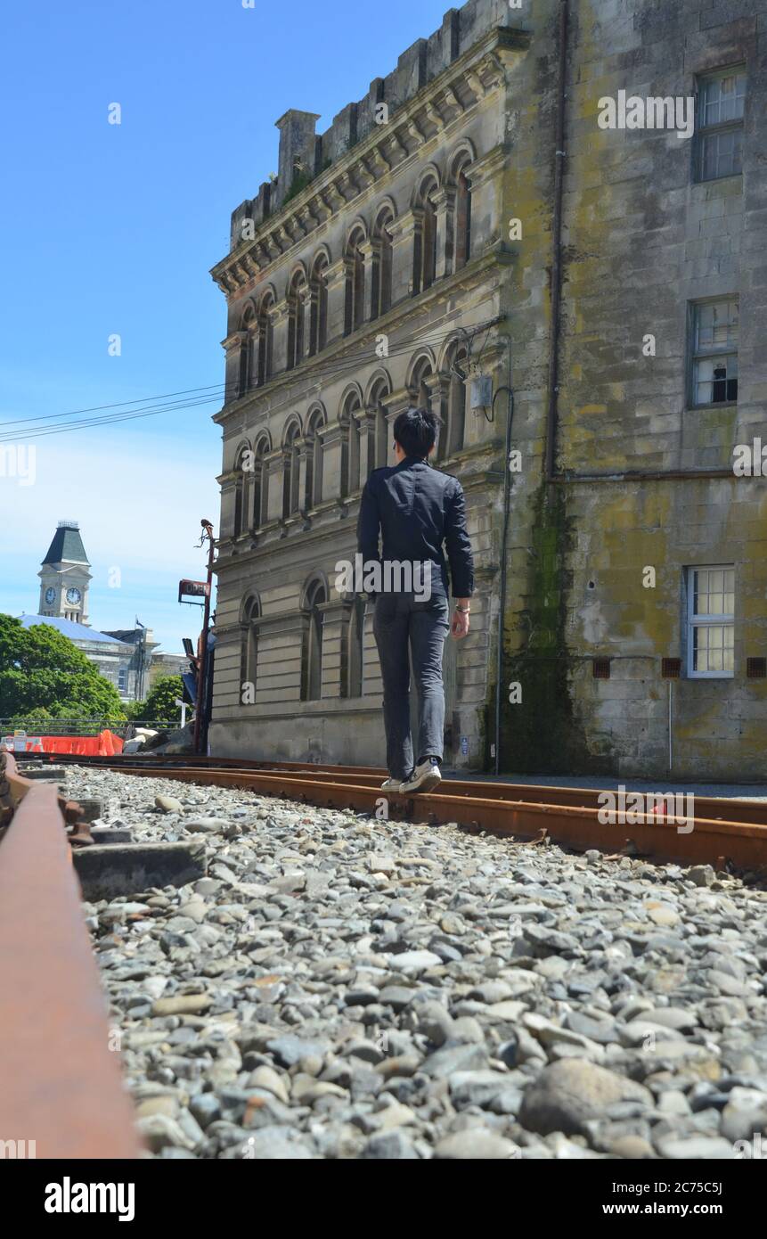 Vista posteriore di un uomo che cammina sulla strada ferroviaria della città vecchia di Oamaru. Foto Stock