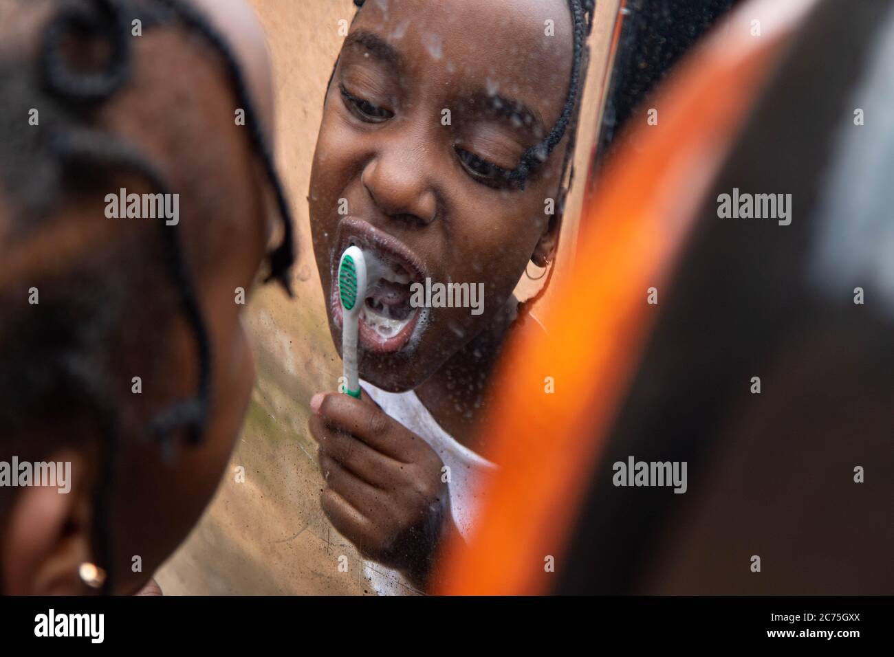 Spazzolare i denti è un'esperienza divertente per Amilia, lei gode molto. I bambini sono a casa grazie al Coronavirus. Karugira, Kigali, Ruanda. Foto Stock