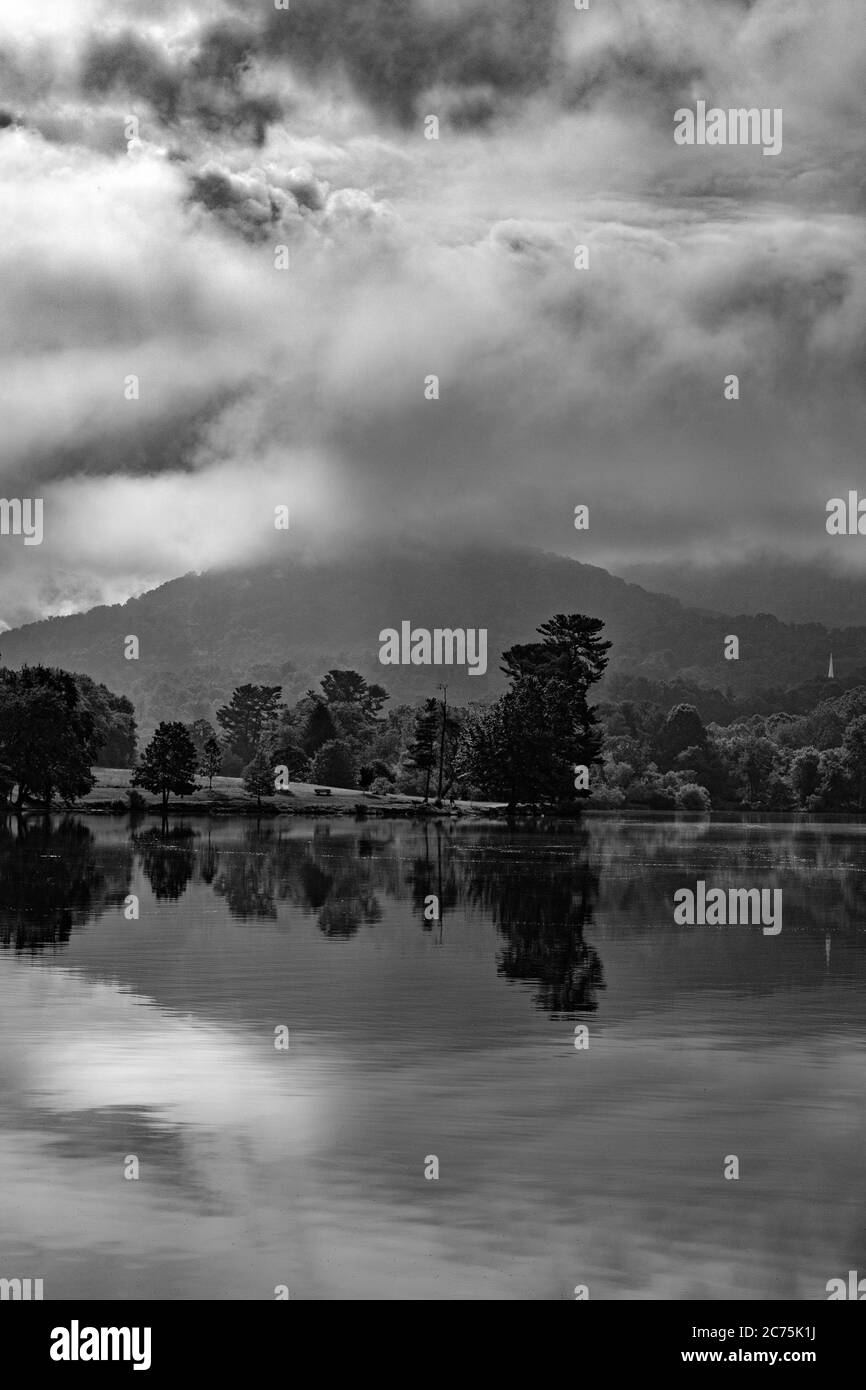 Il riflesso di nuvole, nebbia, montagna e alberi crea simmetria speculare al lago Beaver ad Asheville, NC, USA Foto Stock