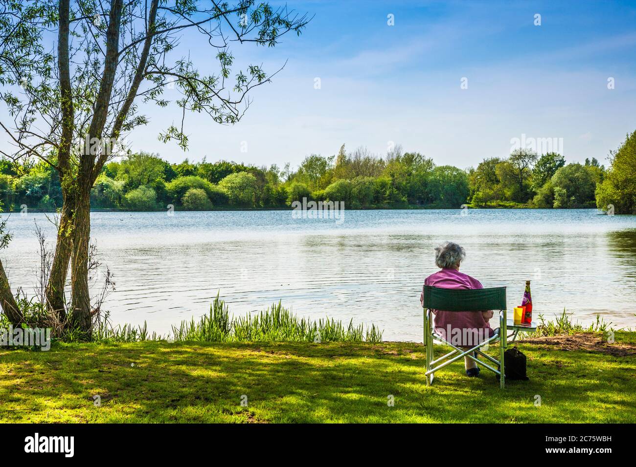 Una donna anziana che gode della vista di uno dei laghi del parco acquatico Cotswold. Foto Stock