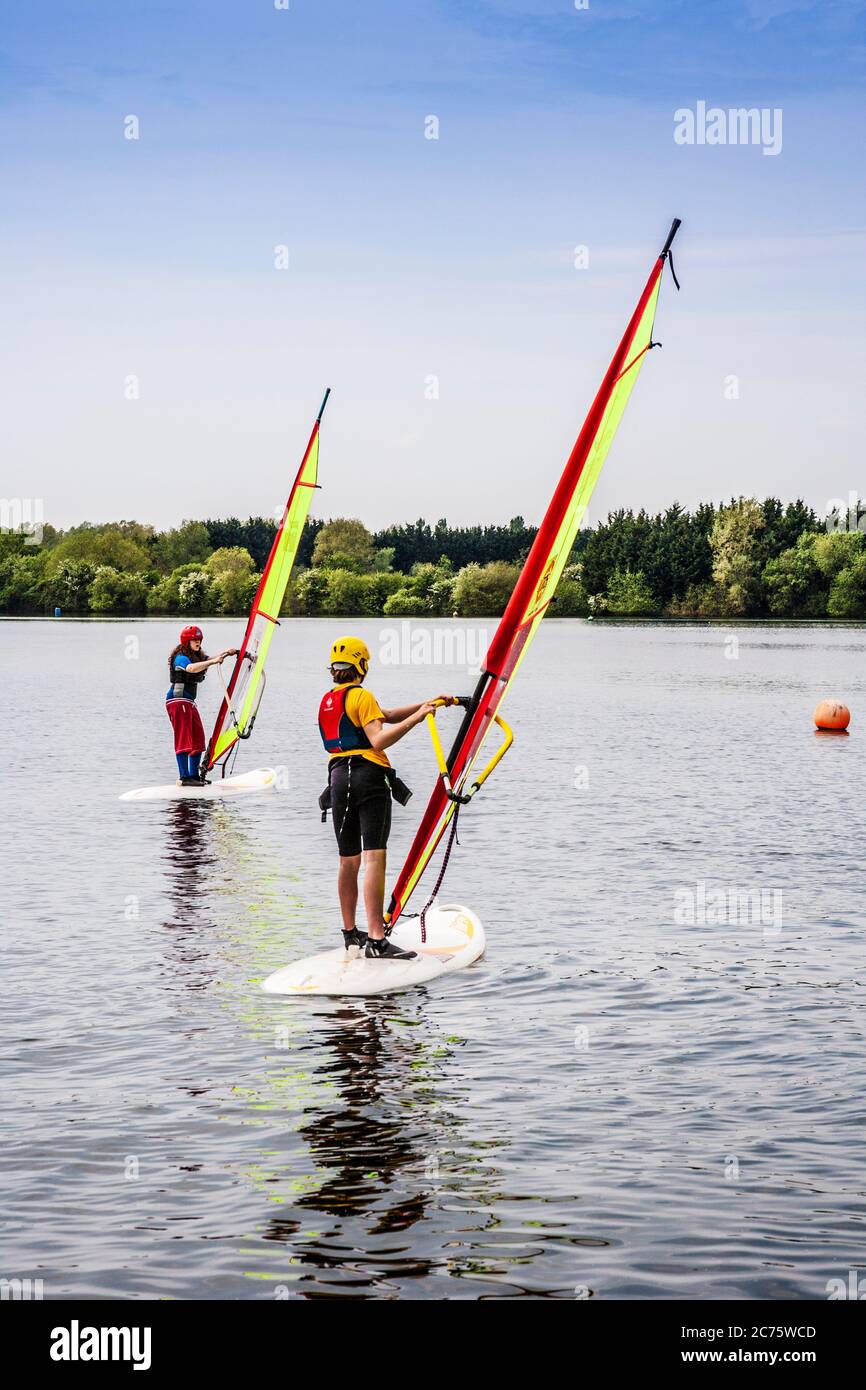 Due giovani imparano a fare windsurf su uno dei laghi del Cotswold Water Park. Foto Stock