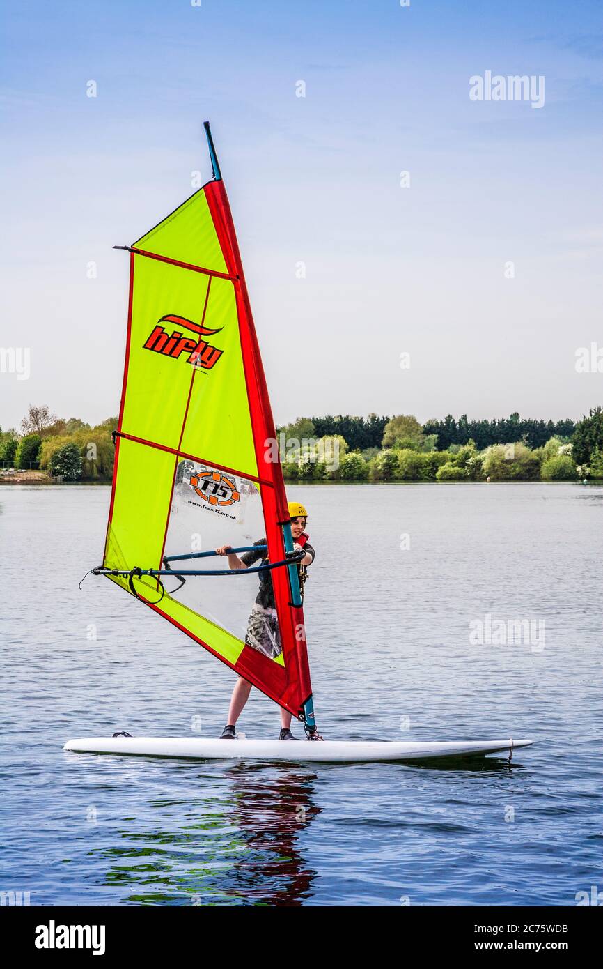 Una giovane persona impara a windsurf su uno dei laghi del Cotswold Water Park. Foto Stock