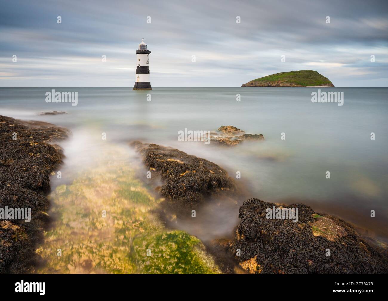 Trwyn Du Faro Penmon punto, Anglesey, è circondato da una marea crescente su un nuvoloso pomeriggio come flusso di nuvole in cielo dietro. Foto Stock Trwyn Du Faro Penmon punto, Anglesey, è circondato da una marea crescente su un nuvoloso pomeriggio come flusso di nuvole in cielo dietro. Foto Stock