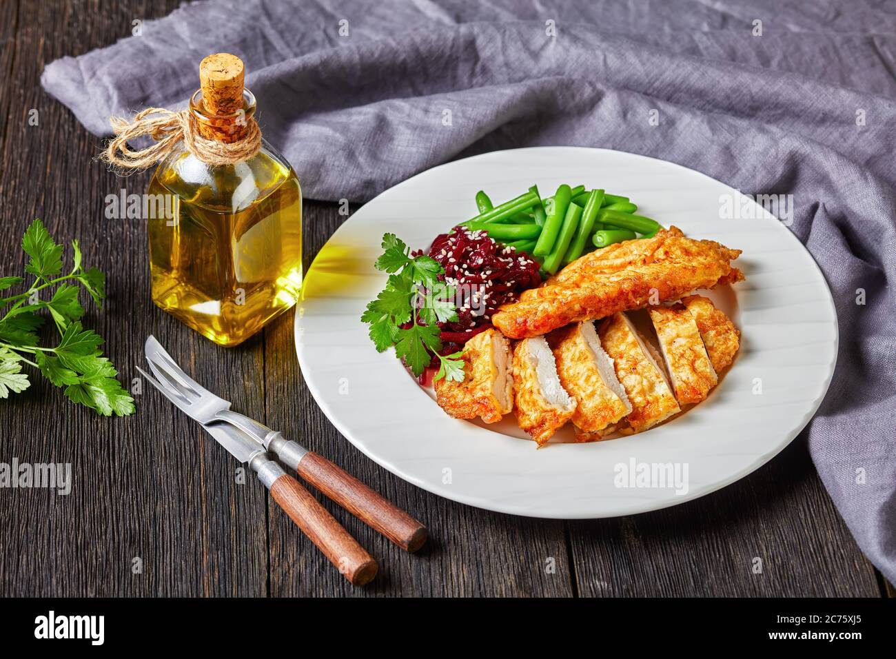 Schnitzel di pollo servito con insalata di barbabietole e fagiolo verde croccante al vapore su un piatto bianco su un tavolo di legno scuro, vista orizzontale dall'alto Foto Stock