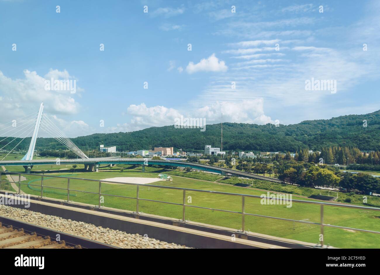 Vista dalla finestra del treno sul moderno ponte automobilistico e alcuni edifici nella zona rurale della corea del Sud Foto Stock