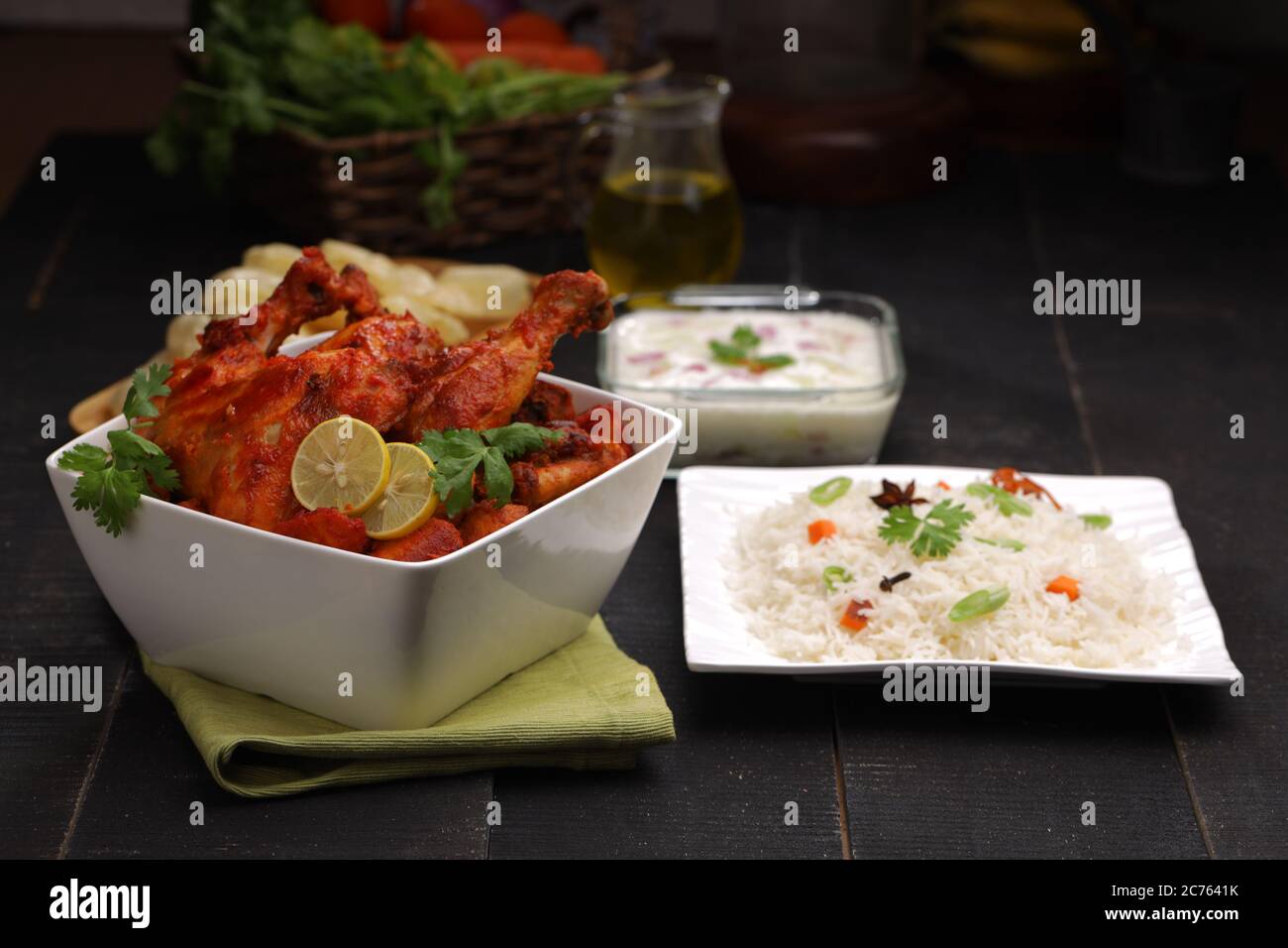 Pollo piccante Tandoori guarnito con foglia di limone e coriandolo in ciotola bianca quadrata con fondo nero, fuoco selettivo Foto Stock