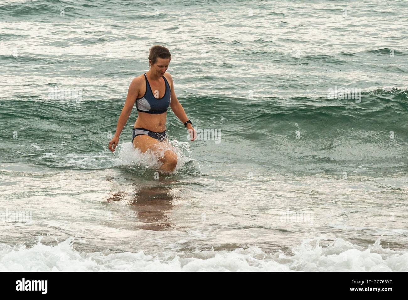 Owenahincha, West Cork, Irlanda. 14 luglio 2020. Una donna esce dall'acqua dopo una nuotata sulla Red Strand Beach, West Cork, nonostante il freddo. Credit: Notizie dal vivo di AG/Alamy Foto Stock