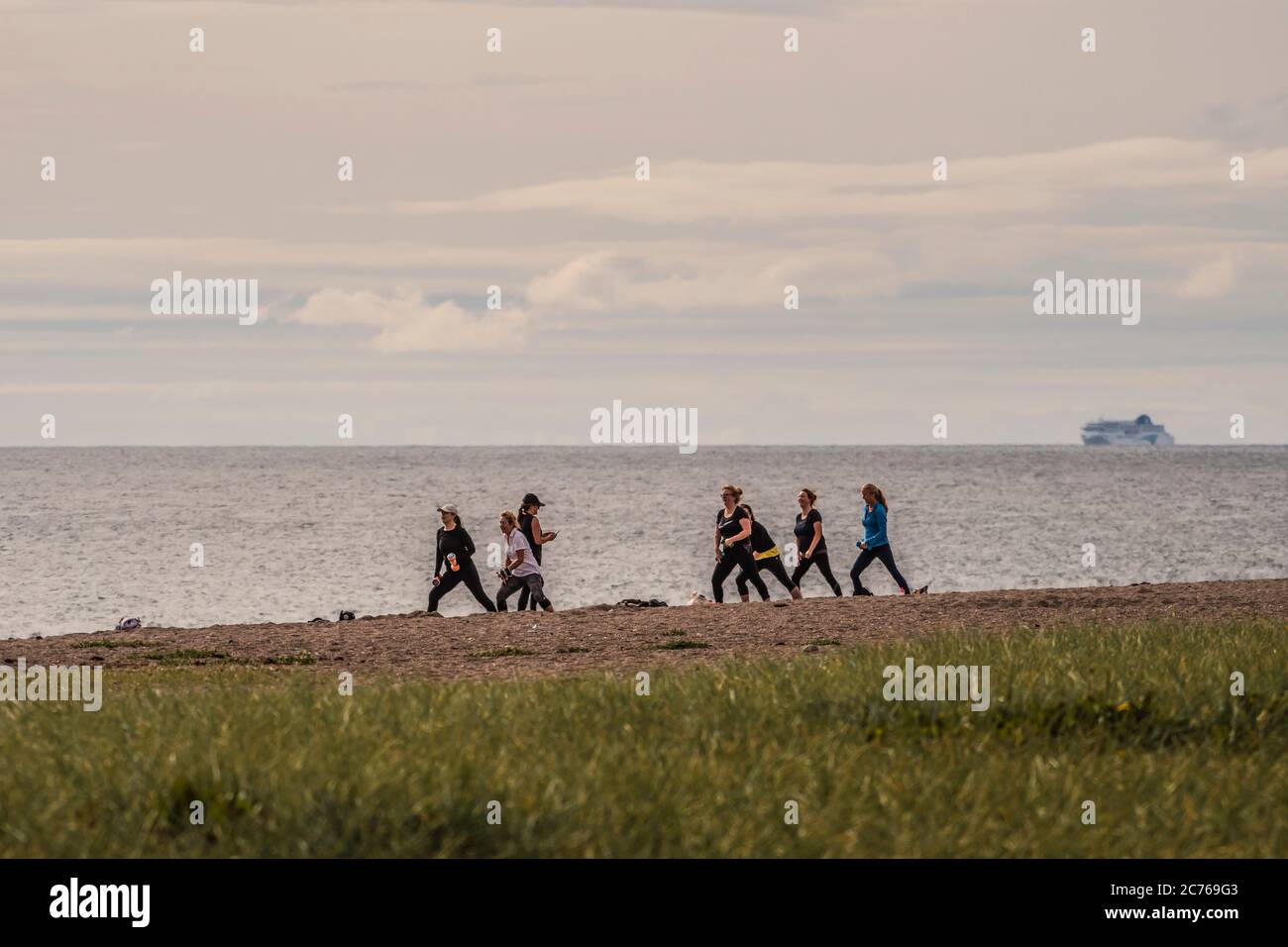 Una lezione di fitness in corso, esercizi di gruppo sulla spiaggia. Foto Stock