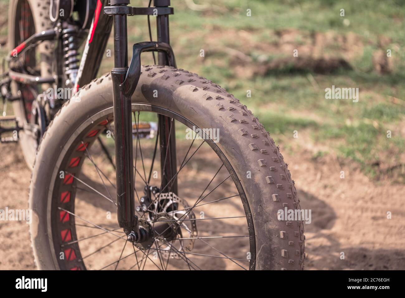 Primo piano di una bicicletta con grandi ruote in campagna. In condizioni di sole, la mountain bike si erge a terra. Foto Stock