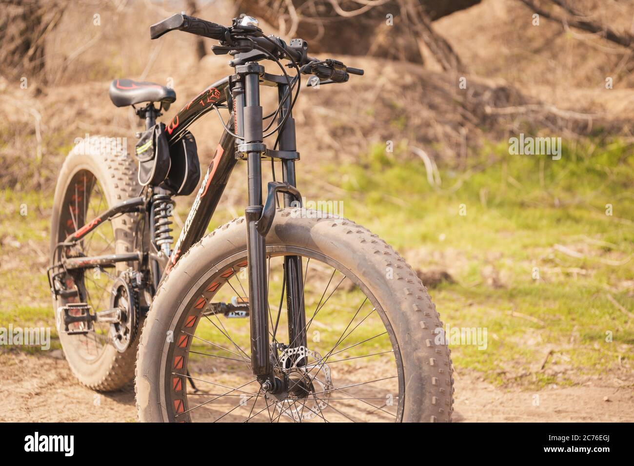 Primo piano di una bicicletta con grandi ruote in campagna. In condizioni di sole, la mountain bike si erge a terra. Foto Stock
