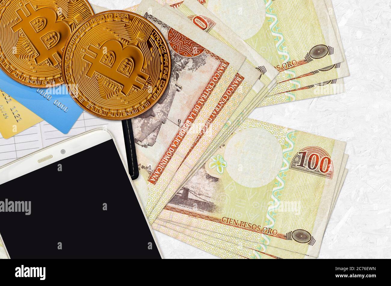 100 pesos dominicani e monete d'oro con smartphone e carte di credito. Concetto di investimento in criptovaluta. Crypto mining o transazione commerciale Foto Stock