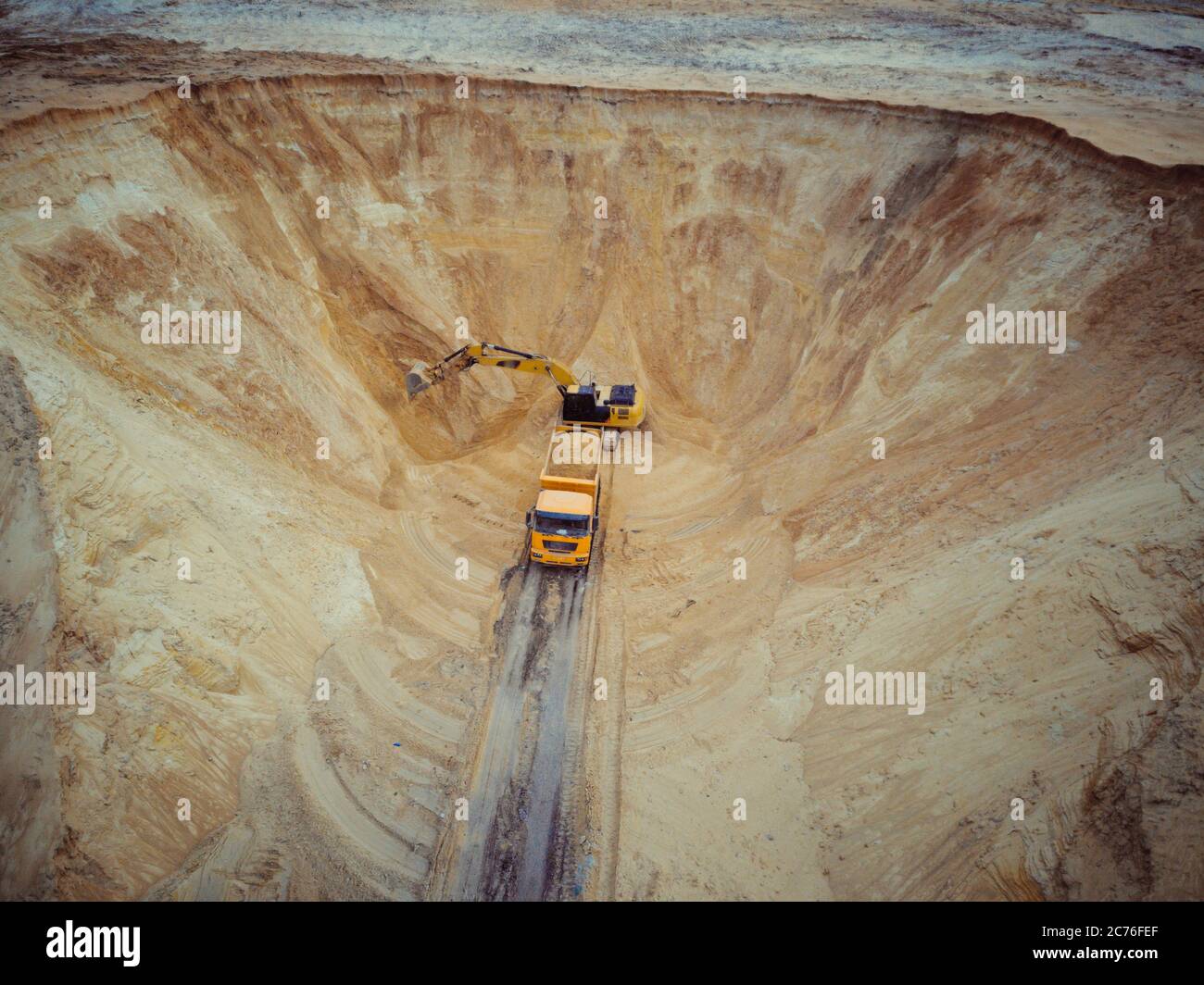 Escavatore e dumper. Vista aerea del carico di sabbia in un carrello. Un macchinario pesante - escavatore e camion stanno lavorando nella cava di sabbia. Foto Stock