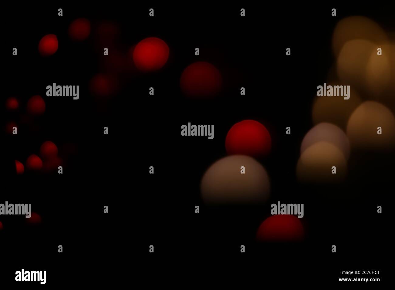 Il bokeh rosso e giallo si illumina su sfondo scuro da macro non focalizzate, create con luci rosse delle fairy e un obiettivo vintage. Foto Stock