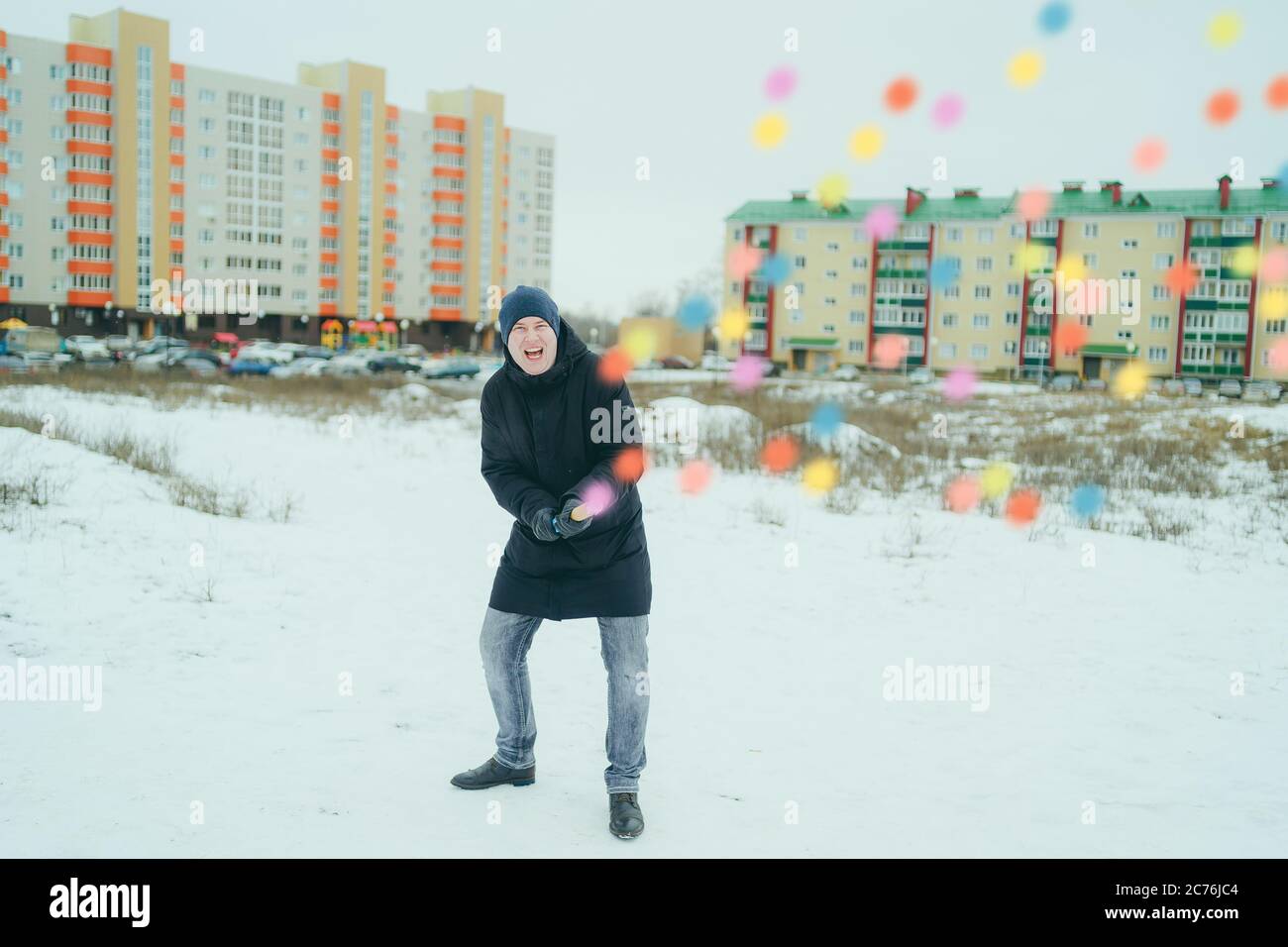 L'uomo emozionale schiocca la petarda dei confetti e ride con gioia. Uomo  adulto in giubbotto nero gioie e papi confetti petard mentre in piedi in  cortile in inverno Foto stock - Alamy
