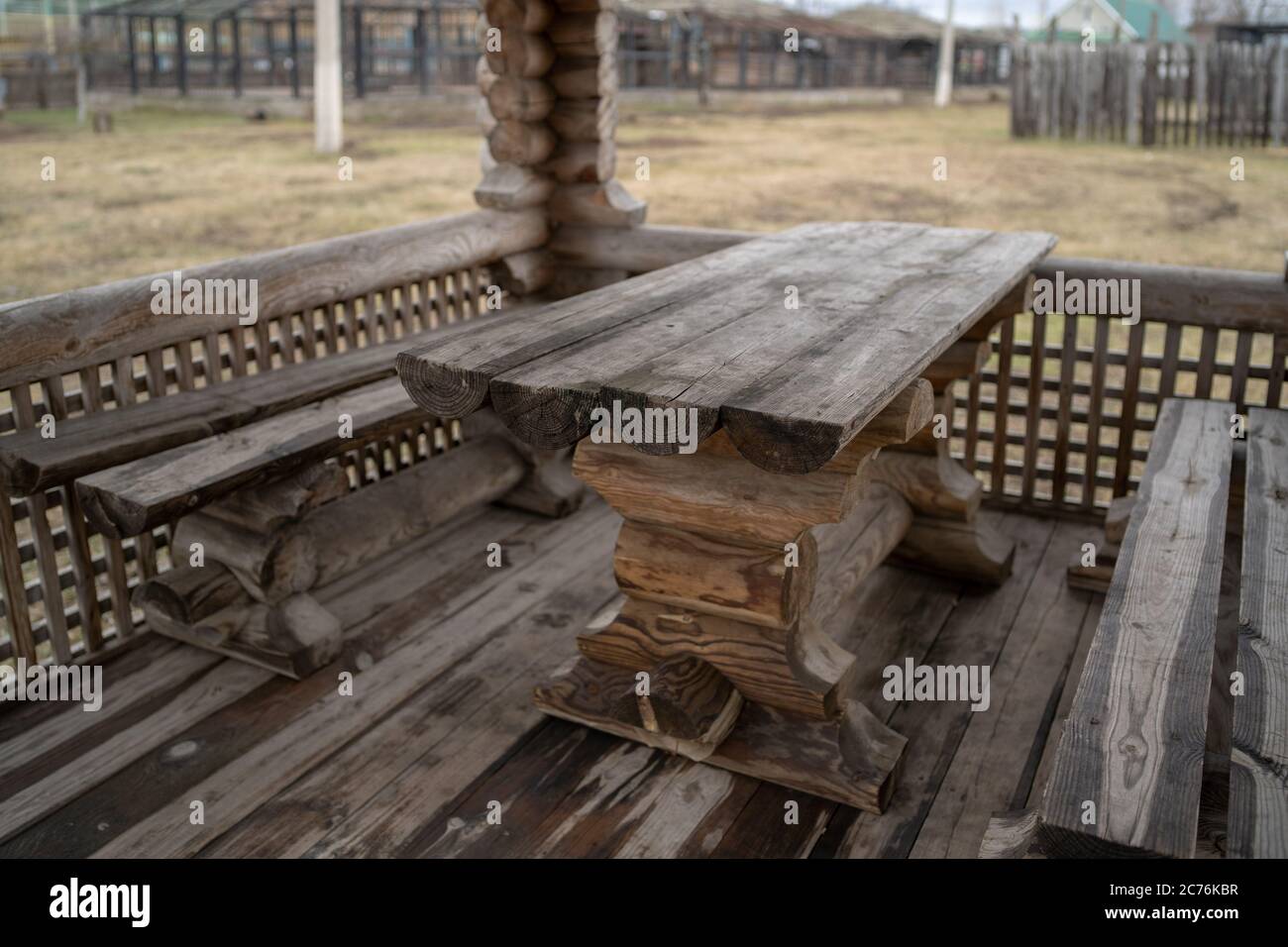 Tavolo in legno con panchine nel parco divertimenti. Terrazza recintata con tavolo e panchine in un parco vuoto durante la cupa giornata autunnale Foto Stock