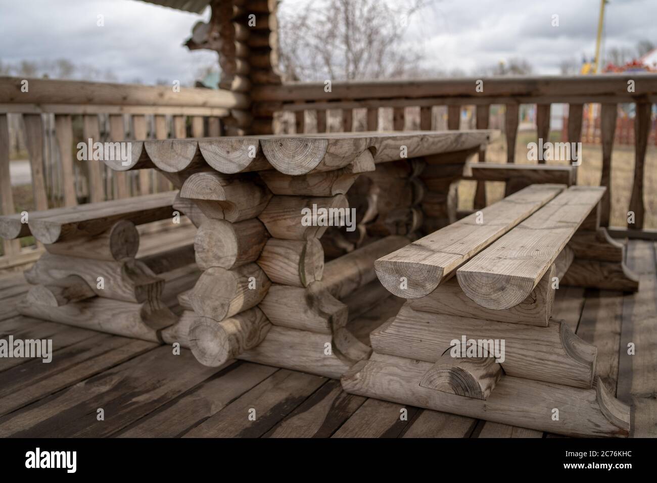 Tavolo in legno con panchine nel parco divertimenti. Terrazza recintata con tavolo e panchine in un parco vuoto durante la cupa giornata autunnale Foto Stock