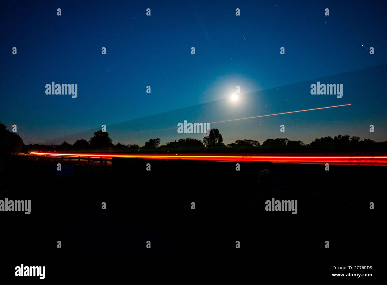 Le luci di un carro che si stese sulla a66 a penrith, passando la luna Foto Stock